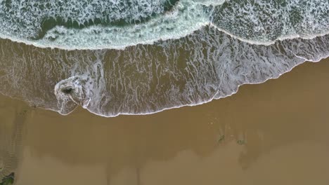 Vista-Superior-De-Las-Espumosas-Olas-Del-Océano-Lavando-La-Playa---Disparo-De-Drones,-Cámara-Lenta