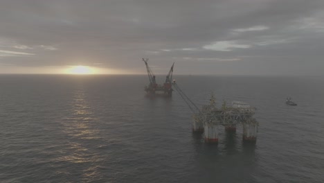 Drone-footage-of-2-oil-rigs-at-sunrise-and-sunset-in-the-open-ocean