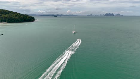 Aéreo:-El-Yate-Navega-Por-Las-Aguas-Turquesas-De-La-Isla-De-Lawa,-Tailandia,-Con-Una-Costa-Exuberante-E-Islas-Distantes-Al-Fondo,-Ideal-Para-Viajes-Y-Temas-De-Ocio