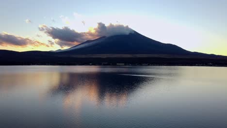 Vista-Del-Atardecer-Del-Monte-Fuji-Reflejada-En-Las-Tranquilas-Aguas-De-Un-Lago,-Nubes-A-La-Deriva