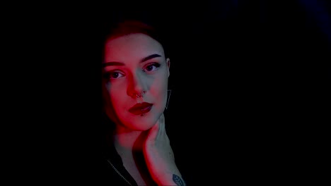 Young-attractive-female-model-posing-in-front-of-a-black-background-with-red-lighting
