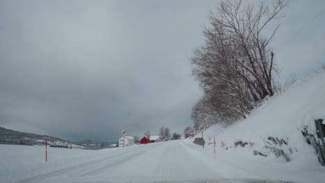 POV-drive-through-Norway's-western-fjord-on-a-snowy-winter-day,-featuring-beautiful-snowy-mountains-and-roads