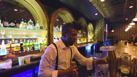 Der-Afroamerikanische-Barkeeper-Verwendet-Ein-Shaker-Tool,-Um-Das-Alkoholische-Getränk-Für-Die-Kunden-Einer-Lokalen-Bar-Zu-Mischen