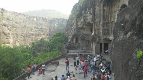 Die-Skulpturen-Am-Eingang-Der-Höhle-26-Der-Ajanta-Höhlen-Mit-Touristen,-Die-Sie-Besichtigen