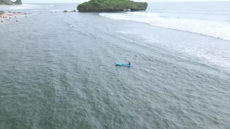Aerial-orbit-drone-shot-of-a-man-was-paddling-a-canoe-with-an-oar-in-the-middle-of-the-beach