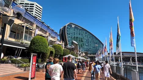 Handheld-clip-walking-along-Cockle-Bay-Wharf-looking-towards-the-W-Hotel,-Darling-Harbour-Sydney