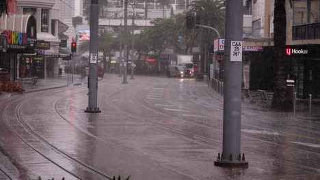 Blick-Auf-Ein-Auto,-Das-Entlang-Des-Surfers-Paradise-Boulevard-Fährt,-Während-Schwere-Regenfälle-Und-Stürme-Weiterhin-Die-Goldküste-In-Anhaltenden-Stürmen-Und-Überschwemmungen-Peitschen