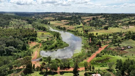 Disparo-De-Drones-Sobre-Tierras-Agrícolas-Rurales-Que-Muestran-árboles,-Caminos-Y-Una-Hermosa-Laguna-Natural