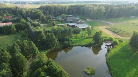 Vista-Aérea-De-La-Granja-En-Polonia-Con-Salón-De-Bodas-Lago-Bosque-árbol-Soleado