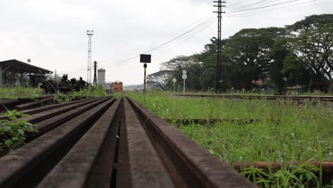 Low-angle,-front-view-of-a-locomotive-of-a-local-passenger-train-slowly-running-on-train-tracks-after-leaving-a-train-station