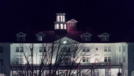 Drone-rises-above-leafless-tree-branches-to-establish-hotel-entrance-and-balcony-with-American-flags-displayed