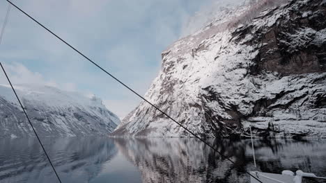 Slow-motion-POV-of-a-winter-ferry-boat-ride-in-Geirangerfjord-to-Geiranger,-Norway,-with-snowy-mountains-and-captivating-fjord-views