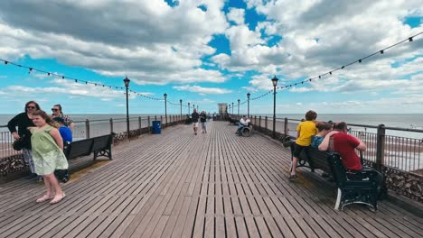 Holidaymakers-gather-on-the-old-wooden-pier-enjoying-the-summer-holidays-in-the-hot-seaside-sun