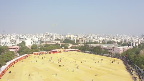 Rajkot-kite-festival-aerial-drone-shot-There-is-a-large-field-surrounded-by-bushes-where-many-tourists-are-flying-different-kites-from-the-field