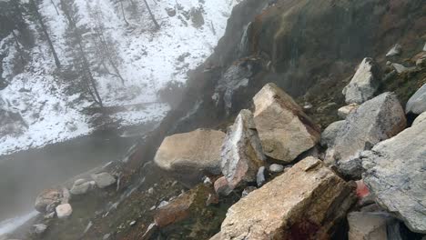 Rocks-On-Mountain-Slope-With-Water-Flowing-In-Mist-In-Winter