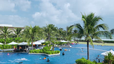 Asian-Tourists-Enjoy-Vacation-Having-Fun-in-Outdoor-Swimming-Pool-on-Sunny-Day-at-Wyndham-Garden-Cam-Ranh-Resort,-Nha-Trang,-Vietnam