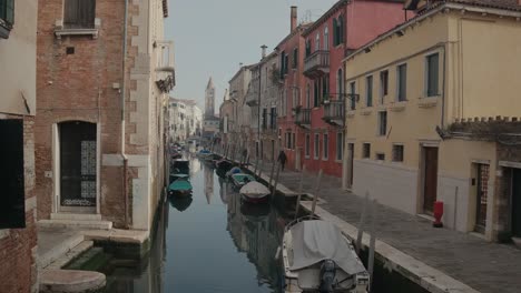 Moores-boats-on-Venetian-waterway-whispers,-colorful-facades-lining