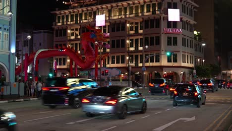 Starker-Autoverkehr-An-Der-Kreuzung-Zwischen-New-Bridge-Road-Und-Upper-Cross-Street-In-Chinatown-Mit-Dem-Yue-Hwa-Gebäude-Und-Der-Drachenkunstinstallation-Zum-Chinesischen-Neujahr-Im-Hintergrund