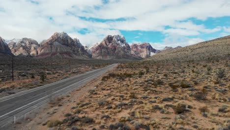 Luftaufnahme-Einer-Drohne-Vom-Red-Rock-Canyon-Schild-An-Der-Interstate-159-Mit-Bergen,-Blauem-Himmel-Und-Wolken-Im-Hintergrund