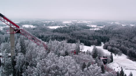 Toma-Aérea-Sobre-El-Bosque-Con-La-Torre-De-Salto-De-Esquí-Tehvandi-Visible-En-Un-Clima-Invernal-Muy-Frío-Y-árboles-Nevados-Por-Todas-Partes