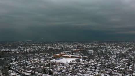 Una-Vista-Aérea-De-Un-Barrio-Suburbano-En-Long-Island,-Nueva-York,-En-Un-Día-Nublado-De-Invierno-Con-Nieve-En-El-Suelo