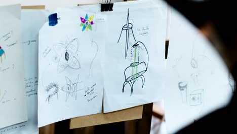 Drafts-of-drawings-by-an-artist-hanging-in-a-workshop,-swaying-with-the-wind
