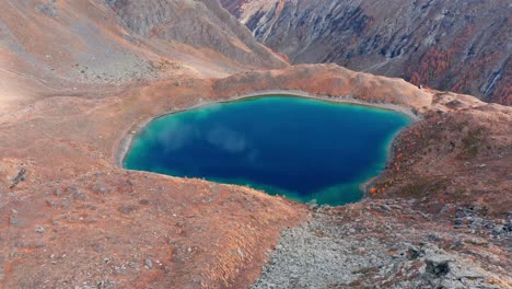 Vibrant-aerial-view-of-Lavodilec-lake-surrounded-by-autumnal-terrain