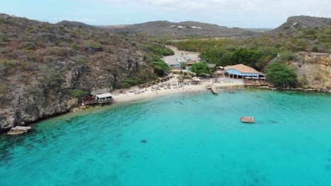 Kokomo-beach-in-curacao-with-turquoise-waters-and-visitors-enjoying-the-sun,-aerial-view