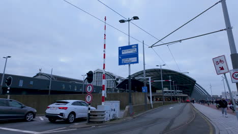 A-railway-crossing-with-a-barrier-near-Amsterdam's-main-train-station,-with-the-iconic-station-architecture-in-the-distance