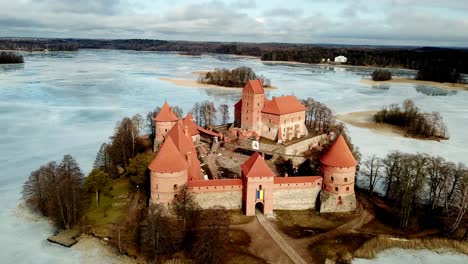 Trakai-Castte-Lithuania,-drone-shot-of-the-medieval-castle-in-a-frozen-lake-on-a-cloudy-day