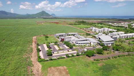 Ecole-du-nord,-mauritius,-surrounded-by-green-fields-under-a-clear-sky,-daylight,-aerial-view