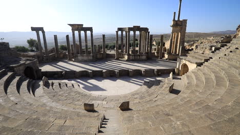 Antiguo-Teatro-Romano-De-Dougga-Con-Arcos-Y-Escalones-Bajo-Un-Cielo-Azul-Claro