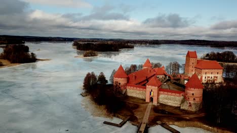Trakai-Castte-Lithuania,-drone-shot-of-the-medieval-castle-in-a-frozen-lake-on-a-cloudy-day