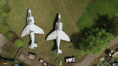 Aerial-view-looking-down-above-two-military-Sea-Harrier-jet-fuselage-on-grassy-Charlwood-display,-Surrey