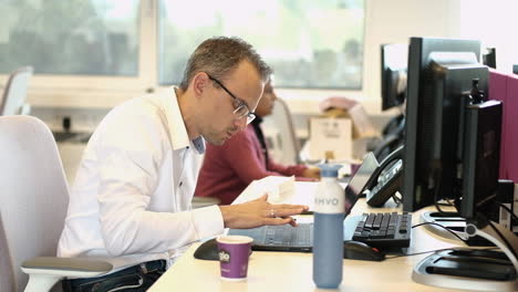 Male-office-employee-wearing-glasses-typing-with-one-finger-on-his-laptop