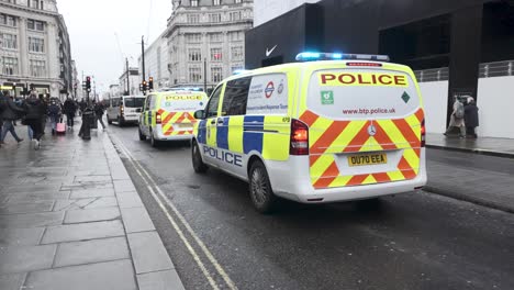 Furgonetas-Policiales-Estacionadas-En-Oxford-Street-En-Londres,-Inglaterra,-Con-Sus-Luces-Intermitentes-Activadas,-Que-Ilustran-El-Concepto-De-Presencia-Policial-Y-Vigilancia-De-La-Seguridad-Pública