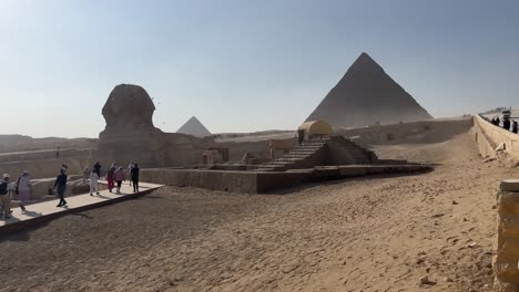 Sphinx-and-pyramids-with-tourists-under-the-clear-sky,-Giza-plateau
