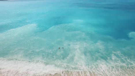 Dos-Personas-Nadando-En-Las-Aguas-Cristalinas-Y-Turquesas-De-La-Playa-De-Myrtos,-Cefalonia-Durante-El-Día,-Vista-Aérea