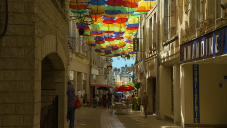 Traditional-alleyway-with-retail-shops-and-restaurants-in-France,-colourful-umbrellas