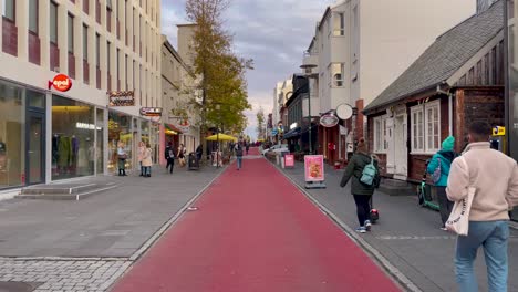 Rot-Gepflasterte-Straße-In-Reykjavik-Mit-Fußgängern-Und-Geschäften-Tagsüber,-Klarer-Himmel