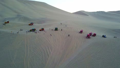 Buggies-Del-Desierto-Estacionados-En-La-Cima-De-Una-Duna-De-Arena-En-El-Oasis-De-Huacachina-Con-Un-Disparo-Aéreo-De-Un-Dron-Inclinándose-Hacia-Arriba,-Perú,-Sudamérica