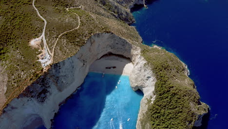 Aerial:-Panoramic-crane-shot-of-Navagio-beach-in-Zante,-Greece-while-the-beach-is-in-shade