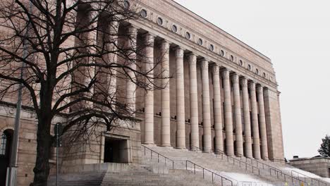 Ramas-De-árboles-Que-Enmarcan-La-Imponente-Fachada-Del-Parlamento-De-Helsinki,-Cielo-Nublado