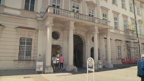 Sonniger-Tag-In-Salzburg,-Blick-Auf-Fußgänger,-Die-An-Einem-Historischen-Europäischen-Gebäude-Mit-Säulen-Vorbeigehen,-Statische-Aufnahme