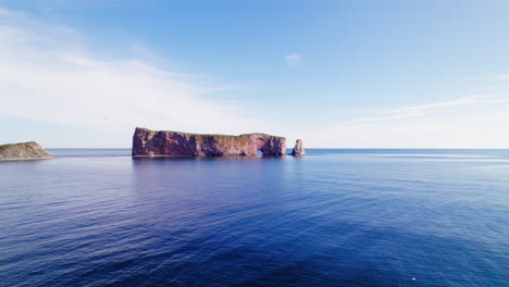 Aerial-drone-view-receding-from-Percé-Rock-above-the-Saint-Lawrence-River-during-a-sunny-day