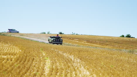 Man-driving-old-1974-land-rover-series-3-rural-road-between-yellow-grain-field