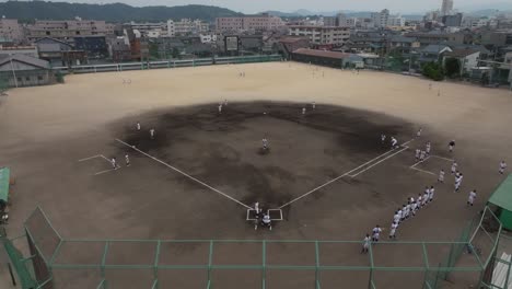 Ball-thrown-to-the-batter-in-a-baseball-Field-game-at-Japanese-City,-Aerial-Drone-Panoramic-Slow-Motion-Shot