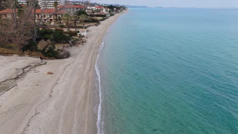 Aerial-view-over-sandy-beach---coastline-with-hotels-and-rolling-waves