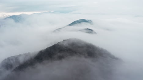 Neblige-Berggipfel,-Die-Aus-Einem-Wolkenmeer-Auftauchen,-Aufgenommen-Am-Frühen-Morgen