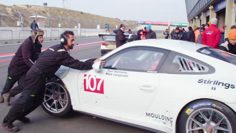 Equipo-De-Pit-Lane-Tirando-De-Un-Costoso-Auto-Deportivo,-Competencia-De-Stock-Car,-Porsche